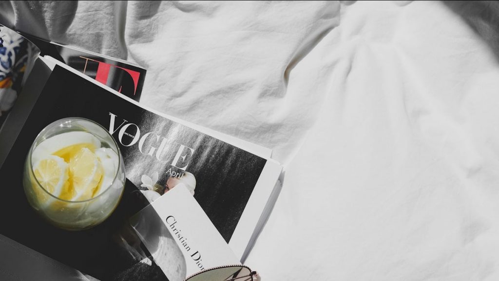 a magazine and sunglasses on a bed