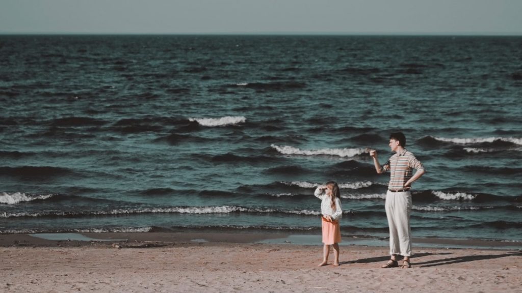 man and woman standing on beach during daytime