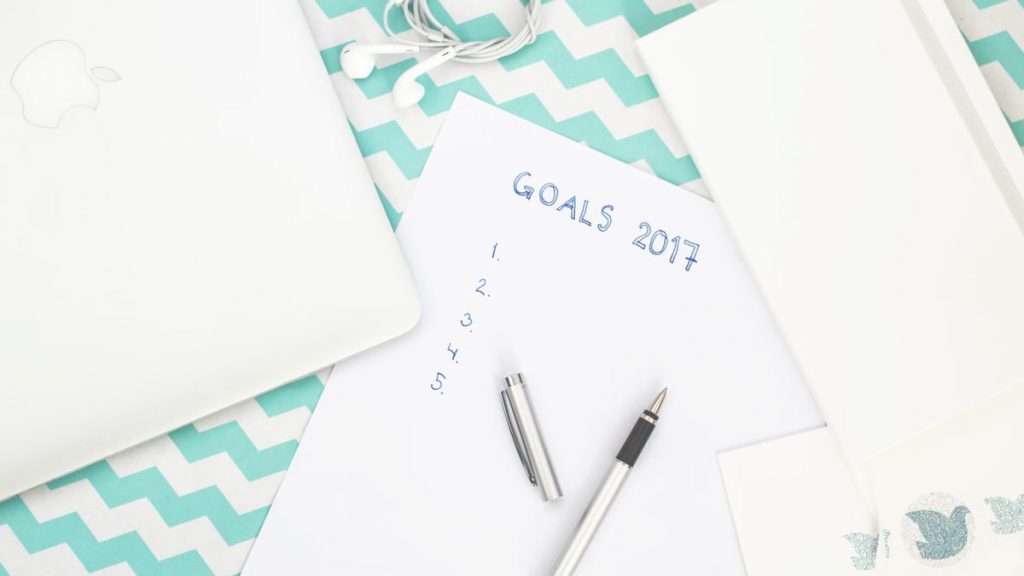 Photo of a workspace featuring a notepad labeled Goals 2017, pen, and laptop for planning.